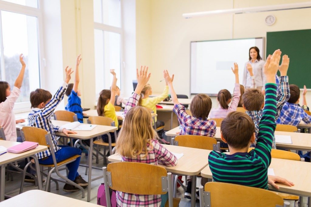 children raising hands inside the classroom