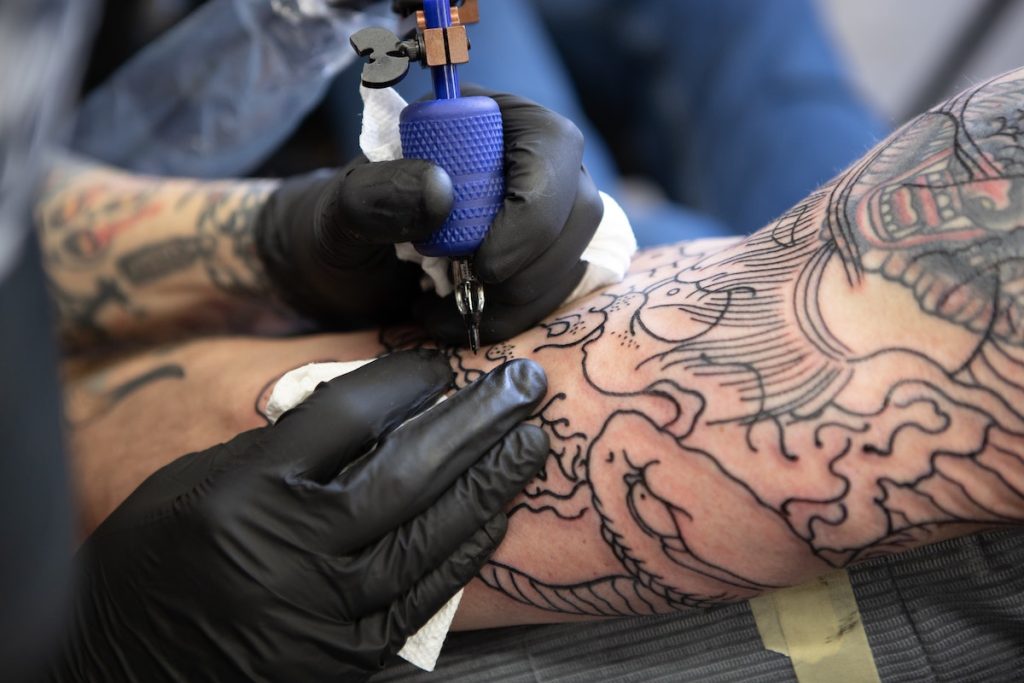 tattoo artist working on an arm