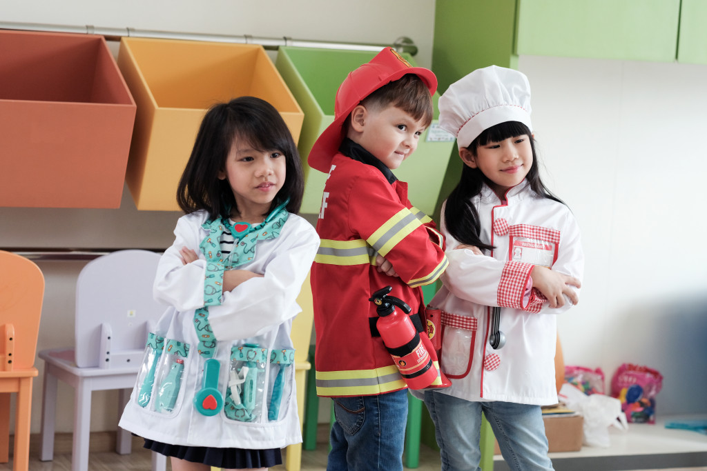 boy and girls role playing as fireman, doctor, and chef