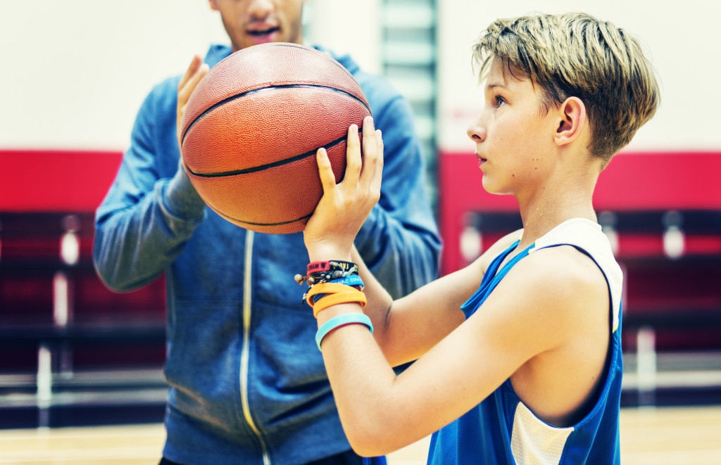 A father and his athlete son playing basketball in a court