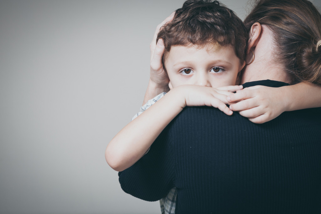 a sad boy hugging his mother