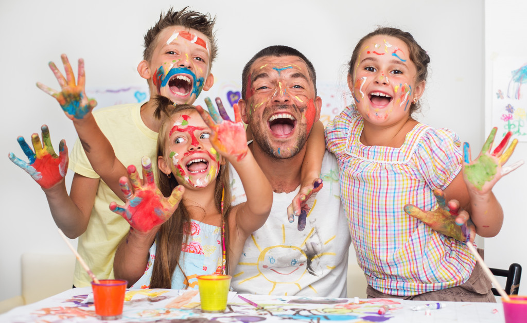 Children and their dad with paint on their hands and faces