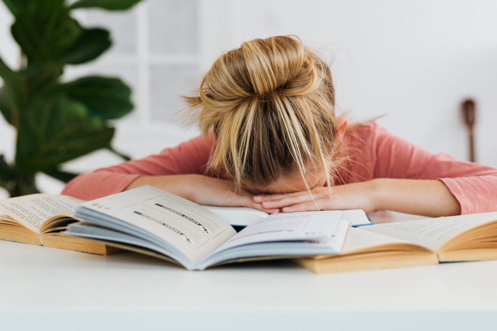 a girl sleeping with her head on open books